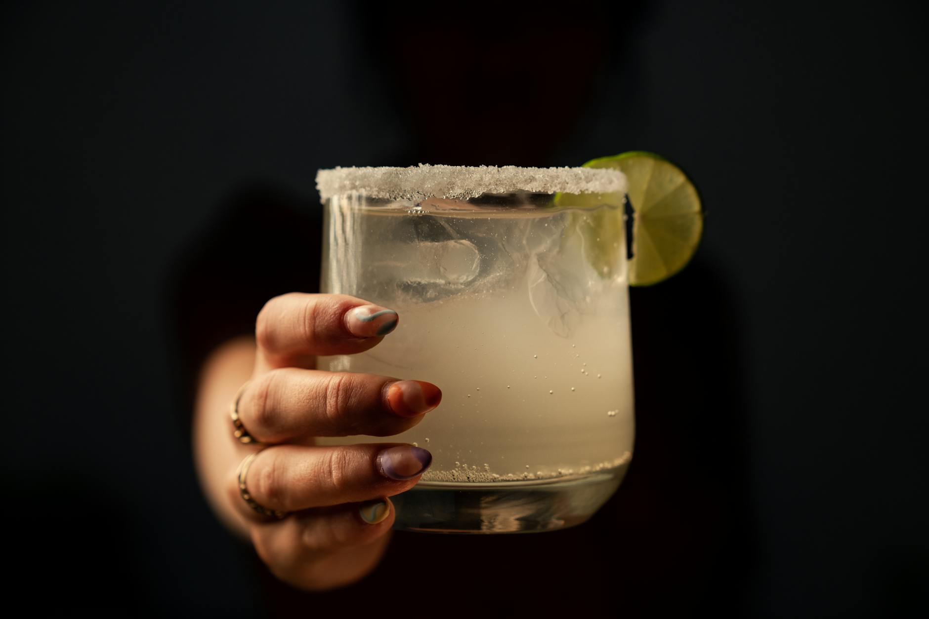 hand holding a margarita on a black background